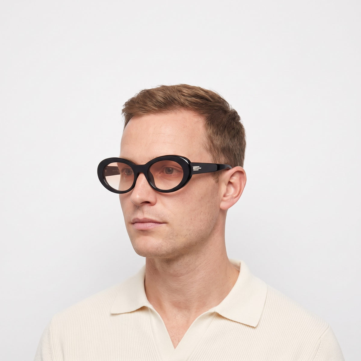 Man in a cream knit polo wearing Belmont bold oval black sunglasses with rose gradient lenses · Velezeco #opt1_2
