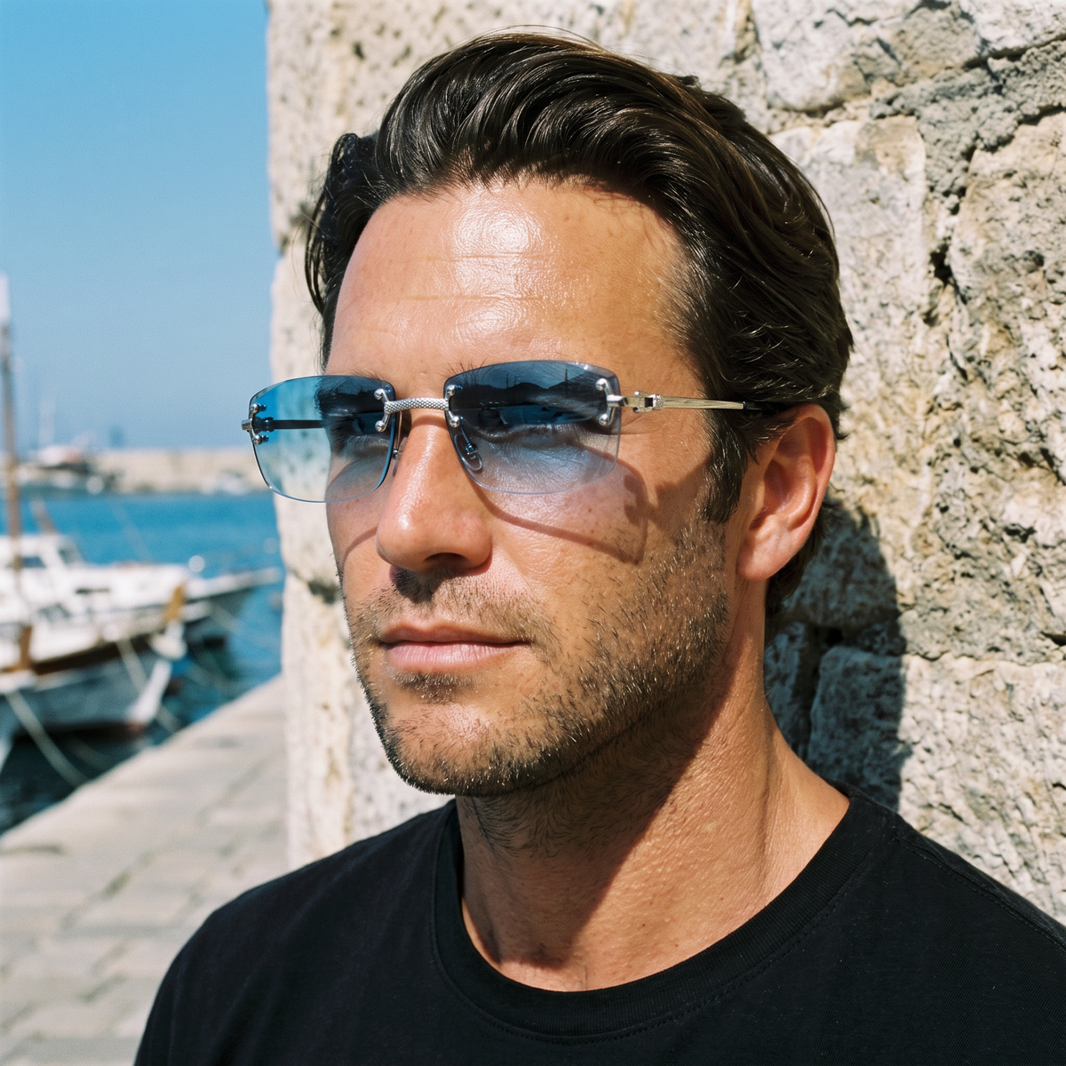 Man at a harbour wearing Cannes rimless sunglasses with blue gradient lenses and silver engraved temples — Velezeco