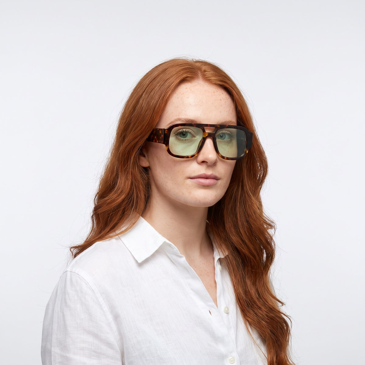Woman in a white linen shirt wearing Crimson oversized square aviator sunglasses in Leopard tortoiseshell with green lenses - Velezeco #opt1_3