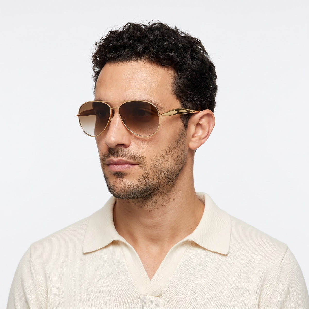 Man in a cream knit polo wearing Duna gold aviator sunglasses with brown gradient lenses · Velezeco #opt1_6