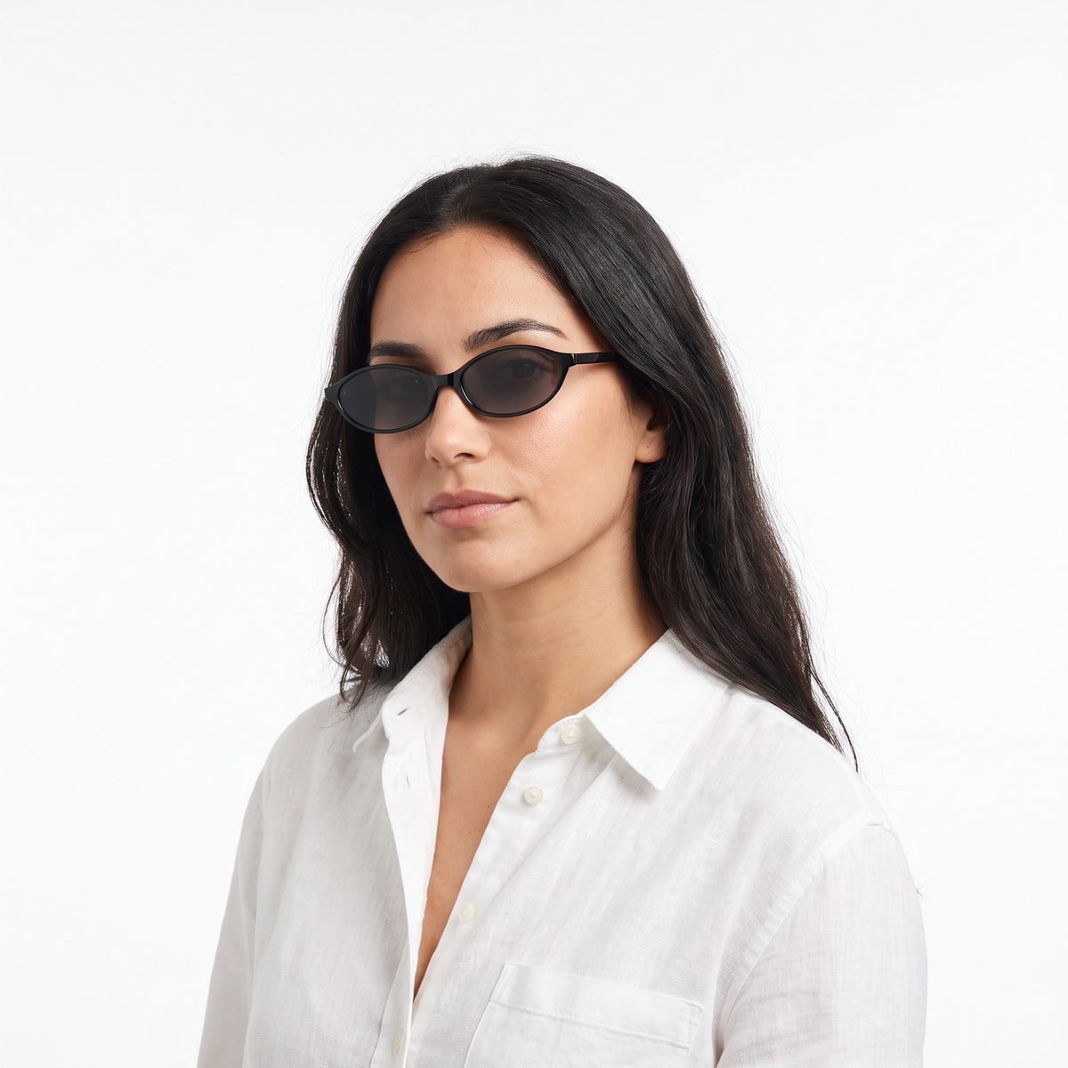 Woman in a white linen shirt wearing Malibu slim oval black sunglasses with smoke grey lenses · Velezeco #opt1_2