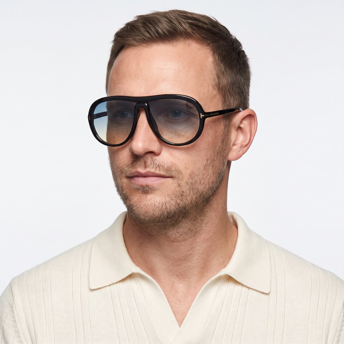 Man in a cream knit polo wearing Marbella black aviator sunglasses with blue to yellow gradient lenses · Velezeco #opt1_1