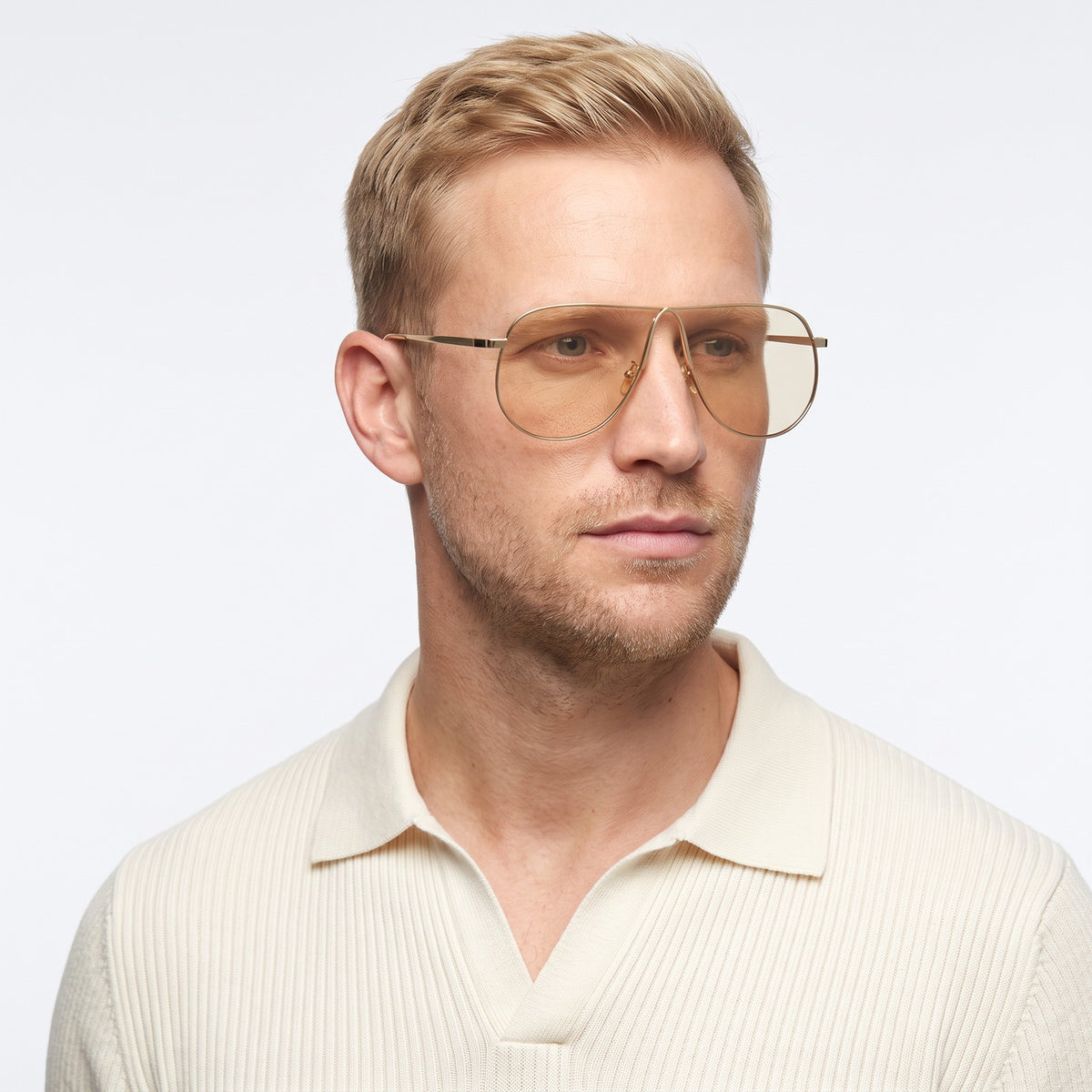 Man in a cream knit polo wearing Mirage oversized gold shield aviator sunglasses with champagne lenses, Champagne · Velezeco #opt1_1