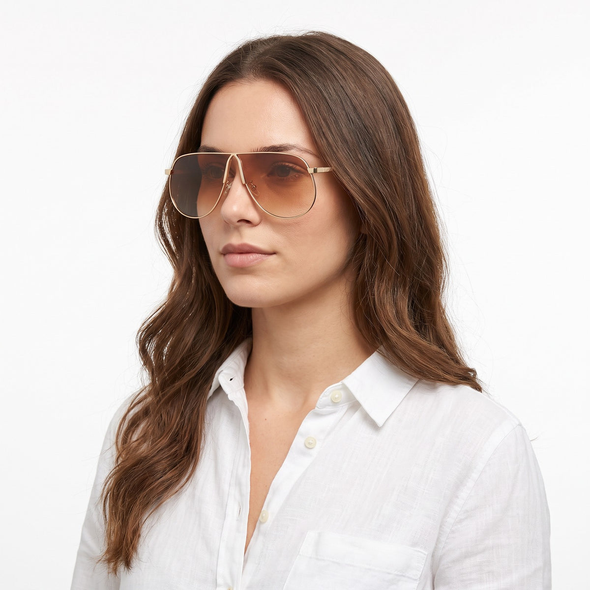 Woman in a white linen shirt wearing Mirage oversized gold shield aviator sunglasses with brown gradient lenses, Gold Gray · Velezeco #opt1_6