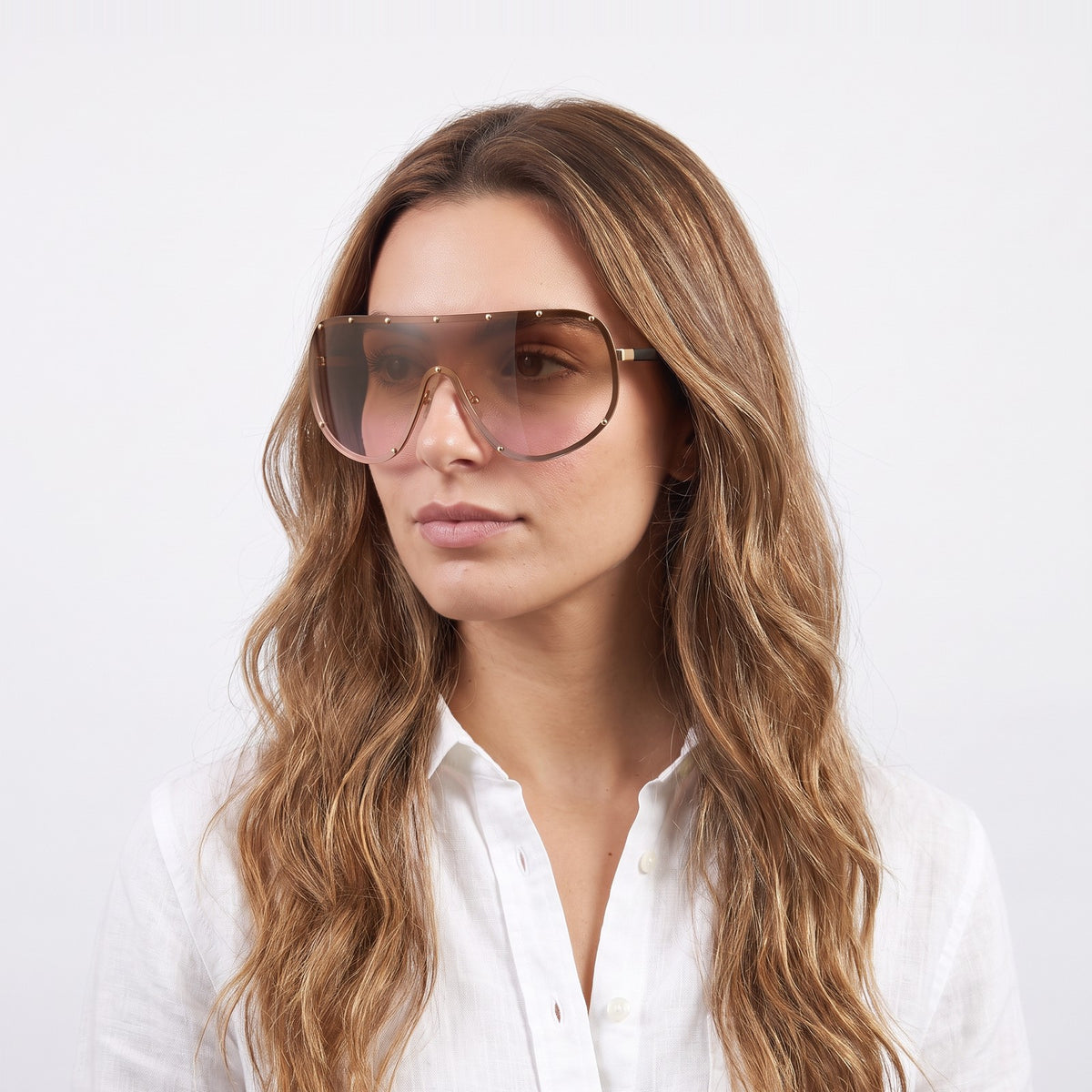Woman in a white linen shirt wearing Mykonos shield sunglasses with gold studded rim and brown-to-pink gradient lens — Velezeco #opt1_4