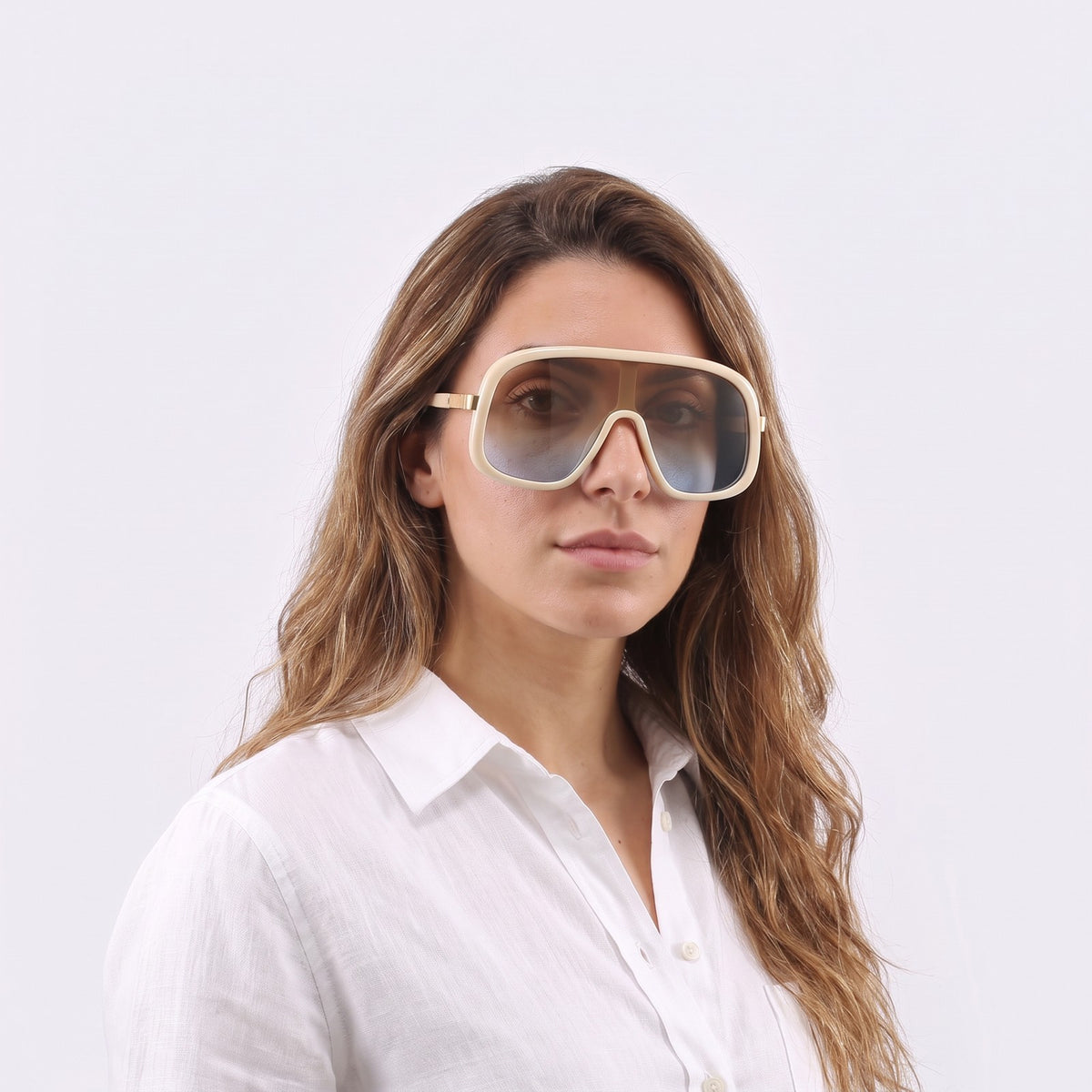 Woman in a white linen shirt wearing Saint-Tropez shield sunglasses with cream beige frame and brown-to-blue gradient lens — Velezeco #opt1_6