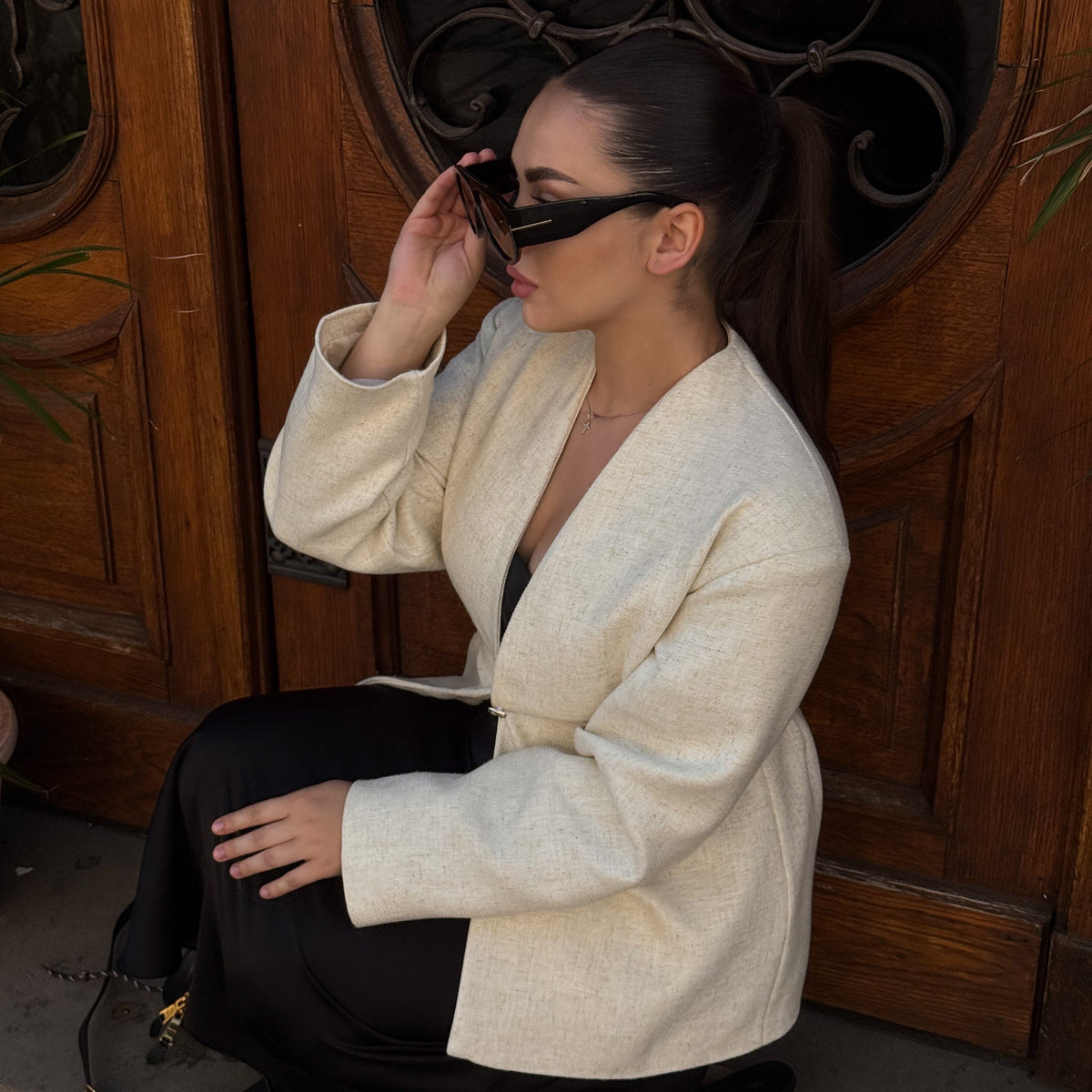 Woman wearing VELEZECO Veneza black oversized aviator sunglasses with brown lenses while seated