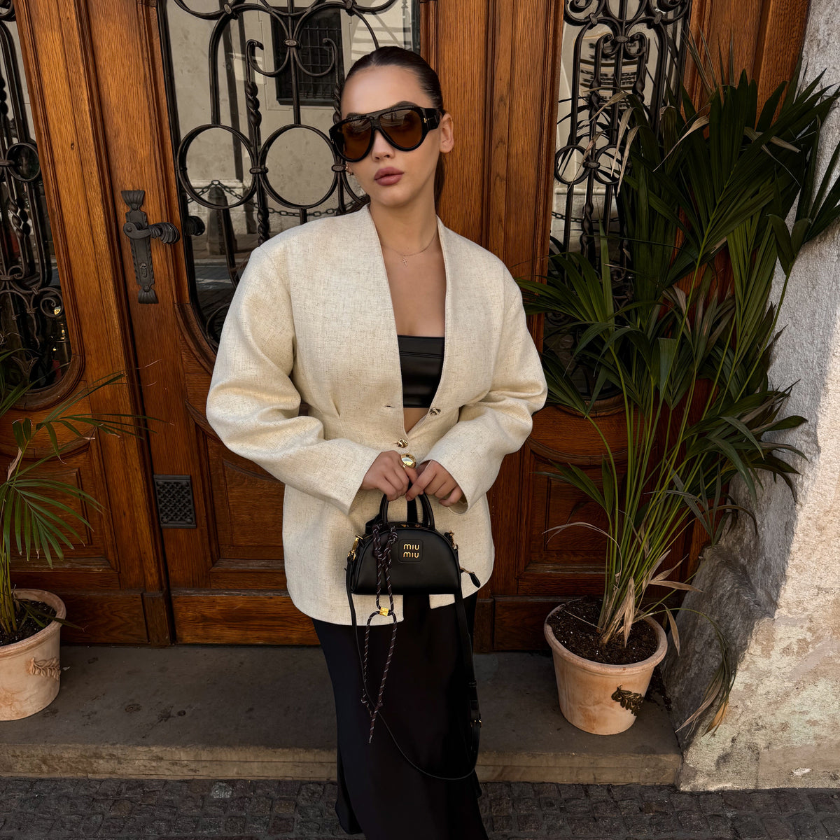Woman wearing VELEZECO Veneza black oversized aviator sunglasses with brown lenses in an elegant street style look