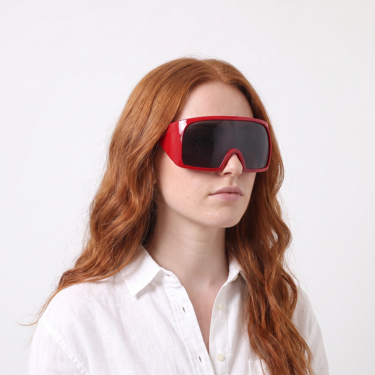 Woman in a white linen shirt wearing Berlin wrap shield sunglasses with glossy red frame and grey lens — Velezeco #opt1_5