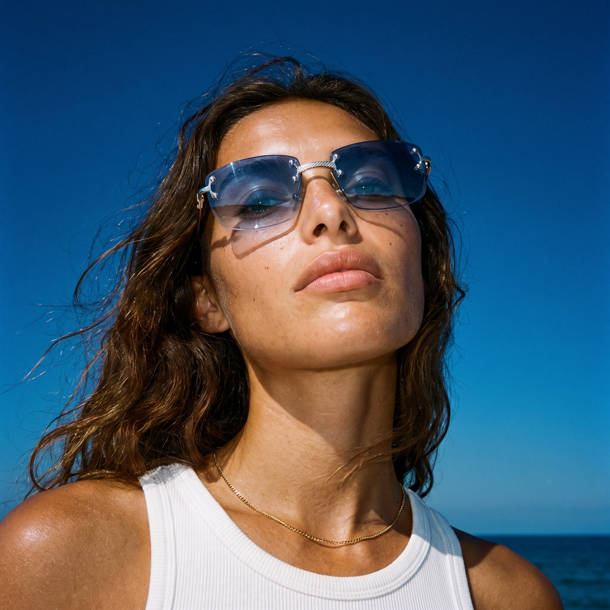 Woman against a blue sky wearing Cannes rimless sunglasses with blue gradient lenses — Velezeco