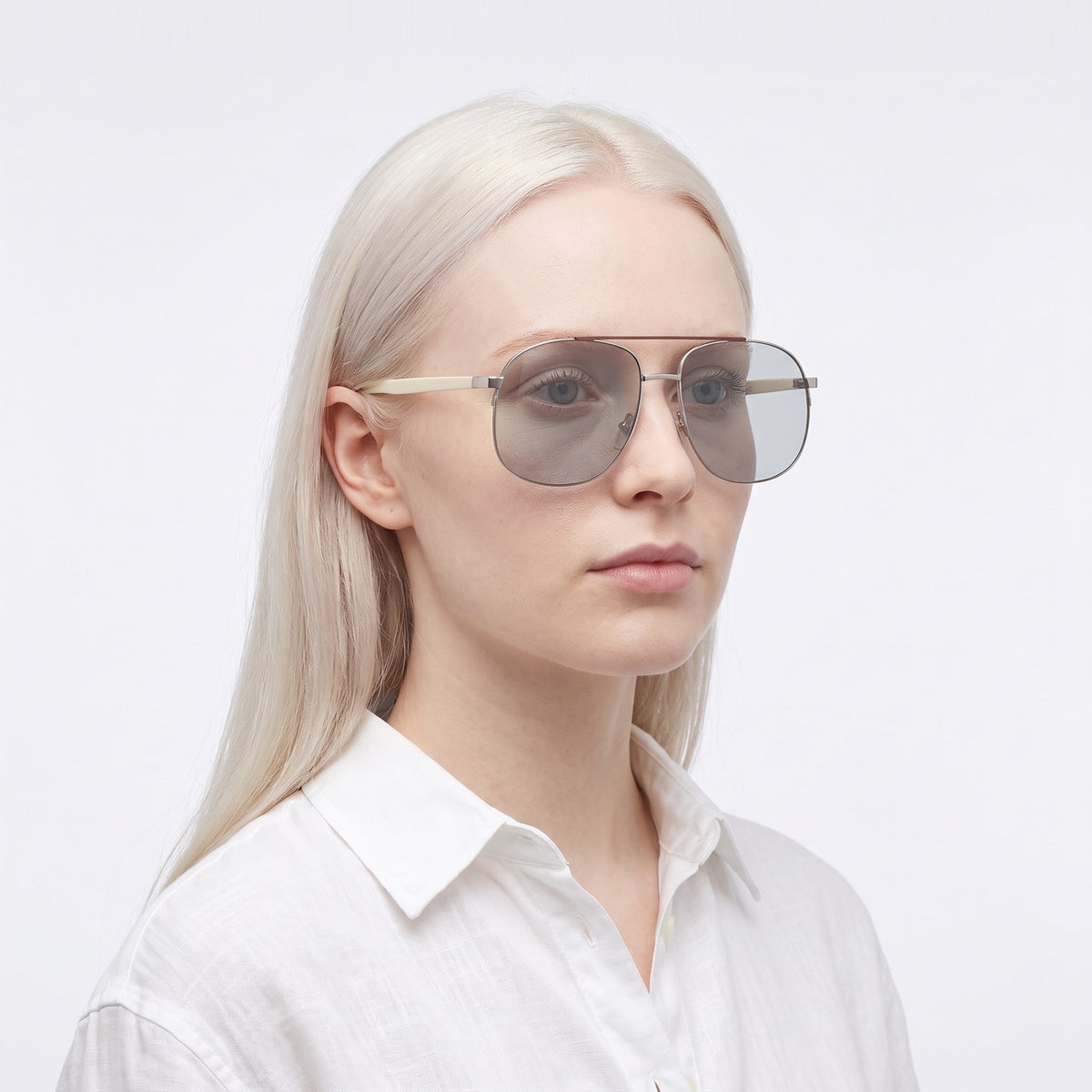 Woman in a white linen shirt wearing Dubai aviator sunglasses with silver double bridge and light grey lenses — Velezeco #opt1_3