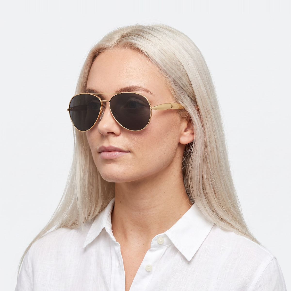 Woman in a white linen shirt wearing Duna gold aviator sunglasses with black lenses · Velezeco #opt1_3