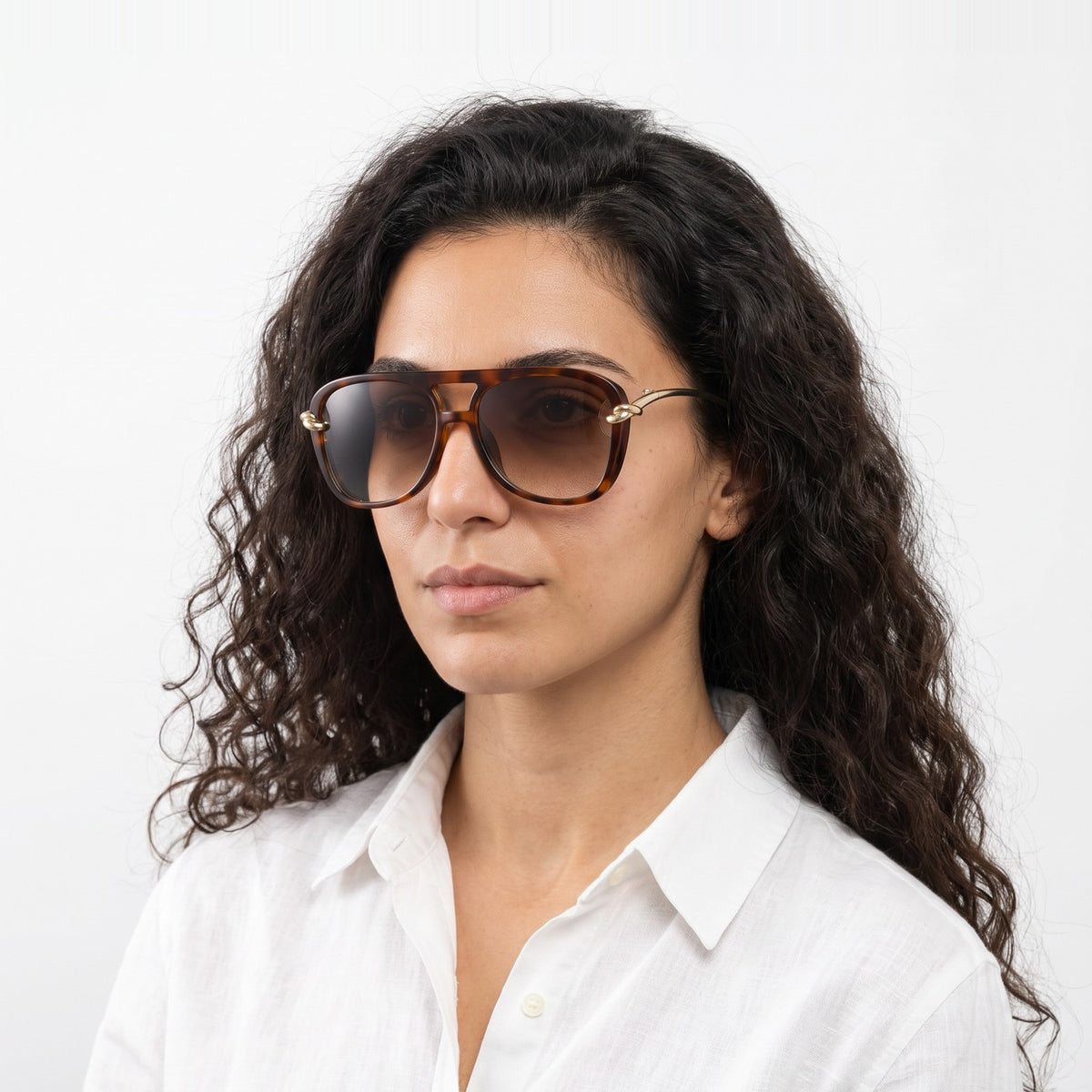 Woman in a white linen shirt wearing Lunna tortoiseshell aviator sunglasses with brown gradient lenses and gold knot temples · Velezeco #opt1_3