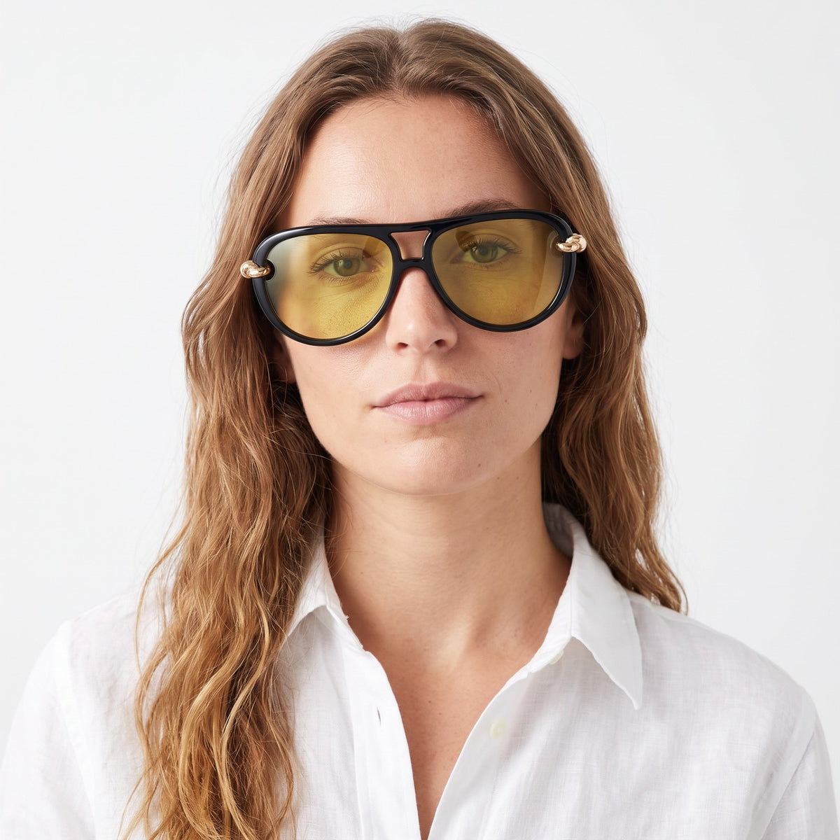 Woman in a white linen shirt wearing Lunna black aviator sunglasses with yellow lenses and gold knot temples · Velezeco #opt1_1
