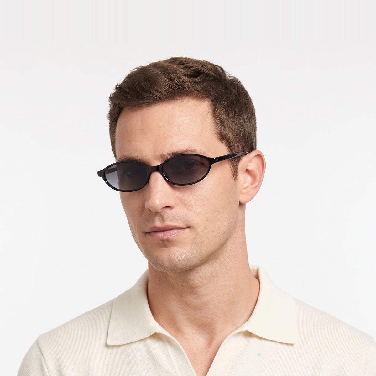 Man in a cream knit polo wearing Malibu slim oval black sunglasses with smoke grey lenses · Velezeco #opt1_2