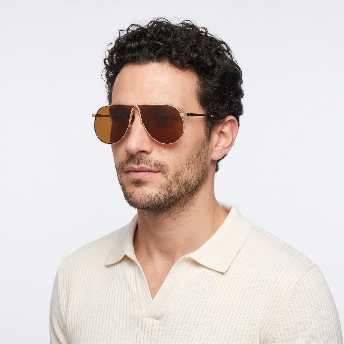 Man in a cream knit polo wearing Mirage oversized gold shield aviator sunglasses with tea brown lenses, All tea · Velezeco #opt1_7