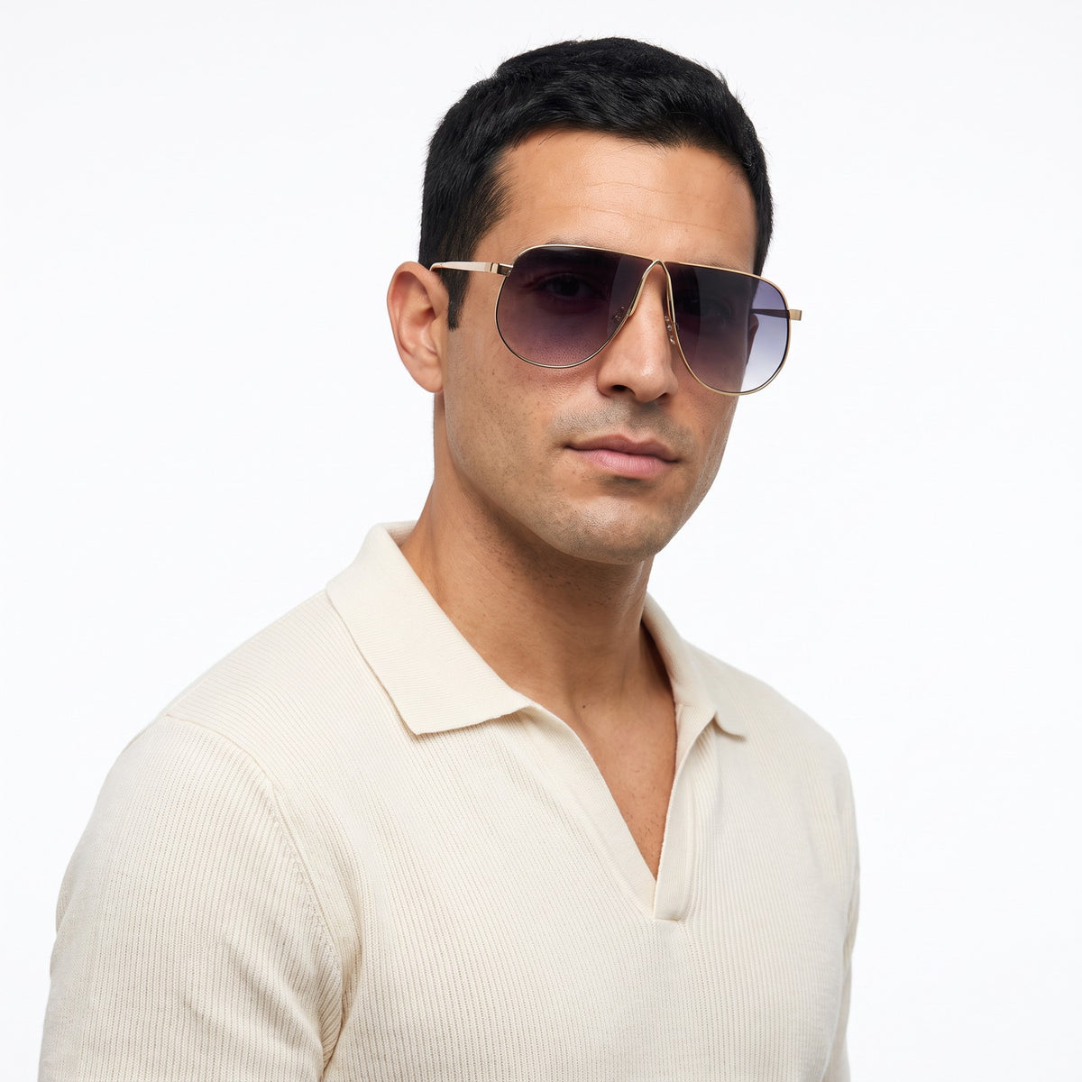 Man in a cream knit polo wearing Mirage oversized gold shield aviator sunglasses with grey gradient lenses, Double Gray · Velezeco #opt1_2