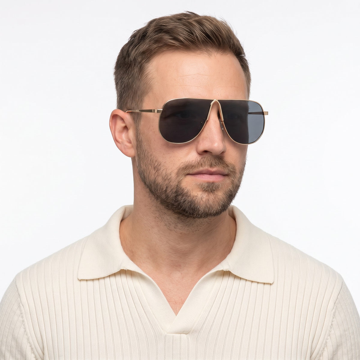 Man in a cream knit polo wearing Mirage oversized gold shield aviator sunglasses with dark grey lenses, Gold · Velezeco #opt1_4