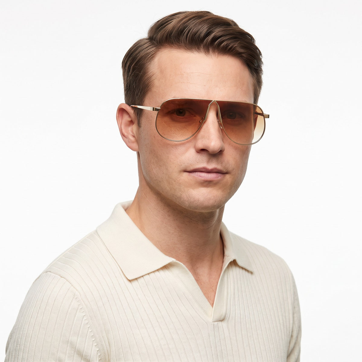 Man in a cream knit polo wearing Mirage oversized gold shield aviator sunglasses with brown gradient lenses, Gold Gray · Velezeco #opt1_6