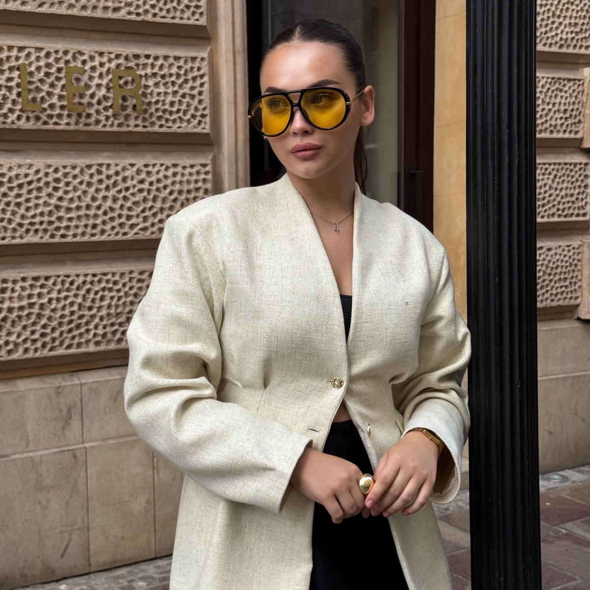 Woman holding The Nimbus black oversized sunglasses with yellow lenses and gold temple details by Velezeco.