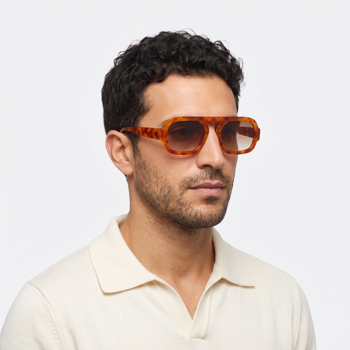 Man in a cream knit polo wearing Vortex amber tortoiseshell square pilot sunglasses with brown gradient lenses · Velezeco #opt1_2