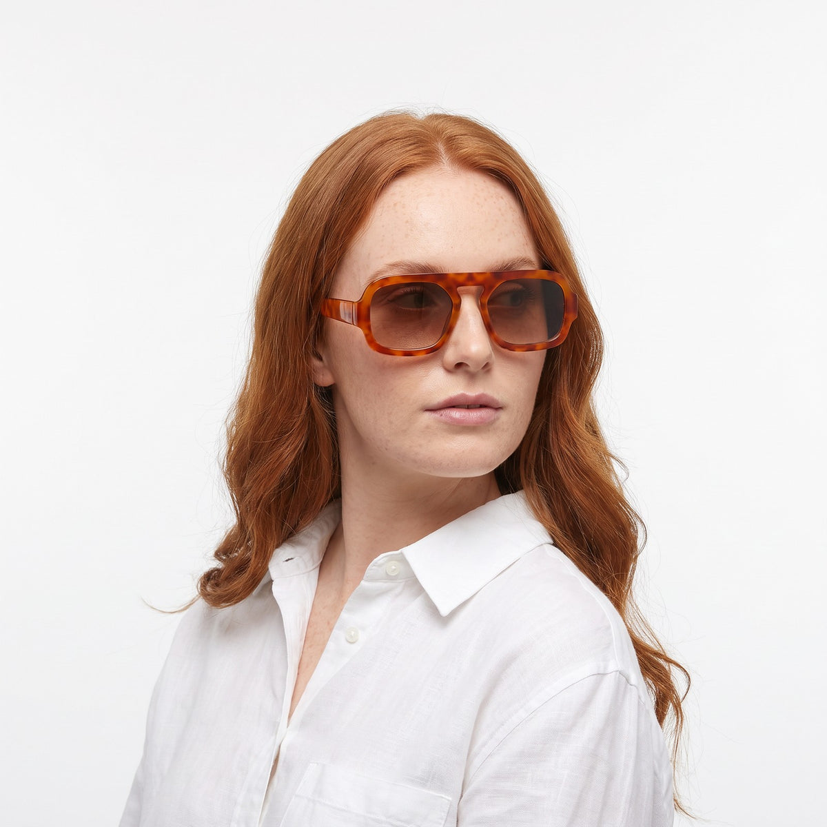 Woman in a white linen shirt wearing Vortex amber tortoiseshell square pilot sunglasses with brown gradient lenses · Velezeco #opt1_2