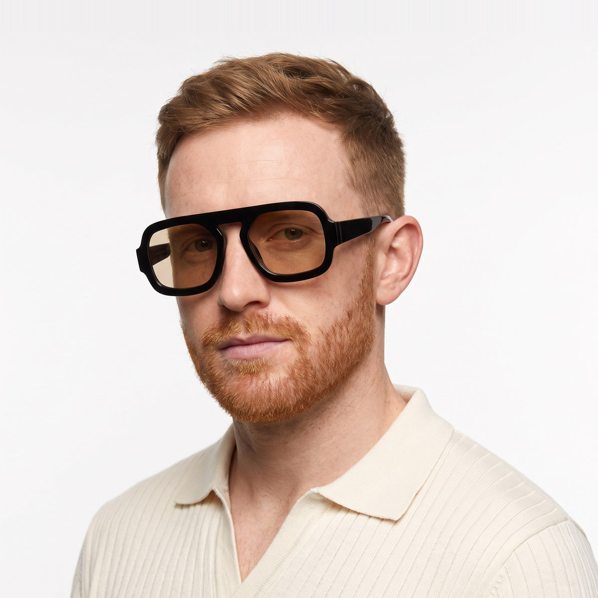 Man in a cream knit polo wearing Vortex black square pilot sunglasses with champagne lenses · Velezeco #opt1_8